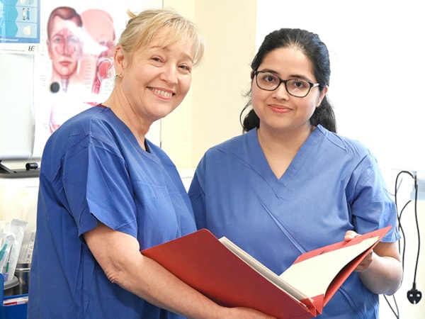 Four nurses gathered around a table making notes on a document